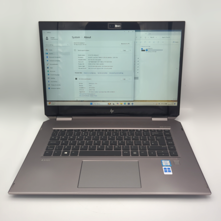 Laptop with Windows 11 displaying system info, open on a clean white surface.