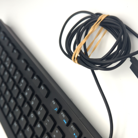 Black keyboard with a coiled USB cable secured with a rubber band on a white background.