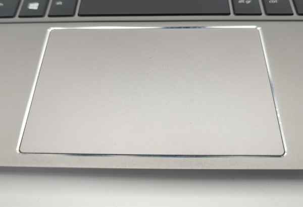 Laptop touchpad close-up next to keyboard, showcasing sleek design and smooth surface.