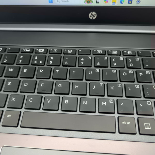 Close-up of a black HP laptop keyboard with visible keys and a part of the screen displaying the start menu.